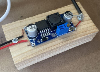 A 5v to 9v converter mounted on a pine wood block. Both sides have poorly soldered conections to some cables, and the potentiometer is tuned to give a 9v output given a 5v input.