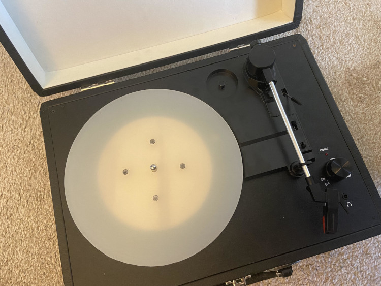 A cloudy, semi transparent plastic platter with 4 metal posts in it, level with its surface.