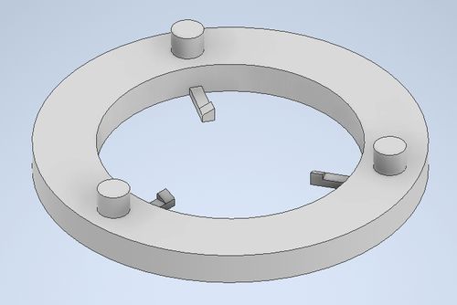 A CAD model of a ring with three posts sticking up on the top face, and 3 thin fingers with triagnles on the tips.